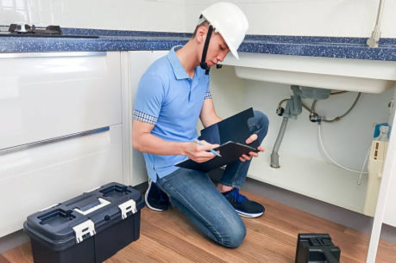 asian male home inspector is checking water leakage situation at kitchen sink asian male home inspector is checking water leakage situation at kitchen sink